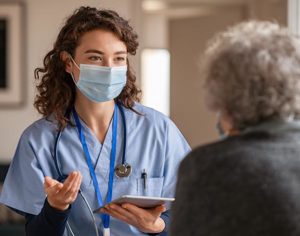 nurse in mask talking to a resident